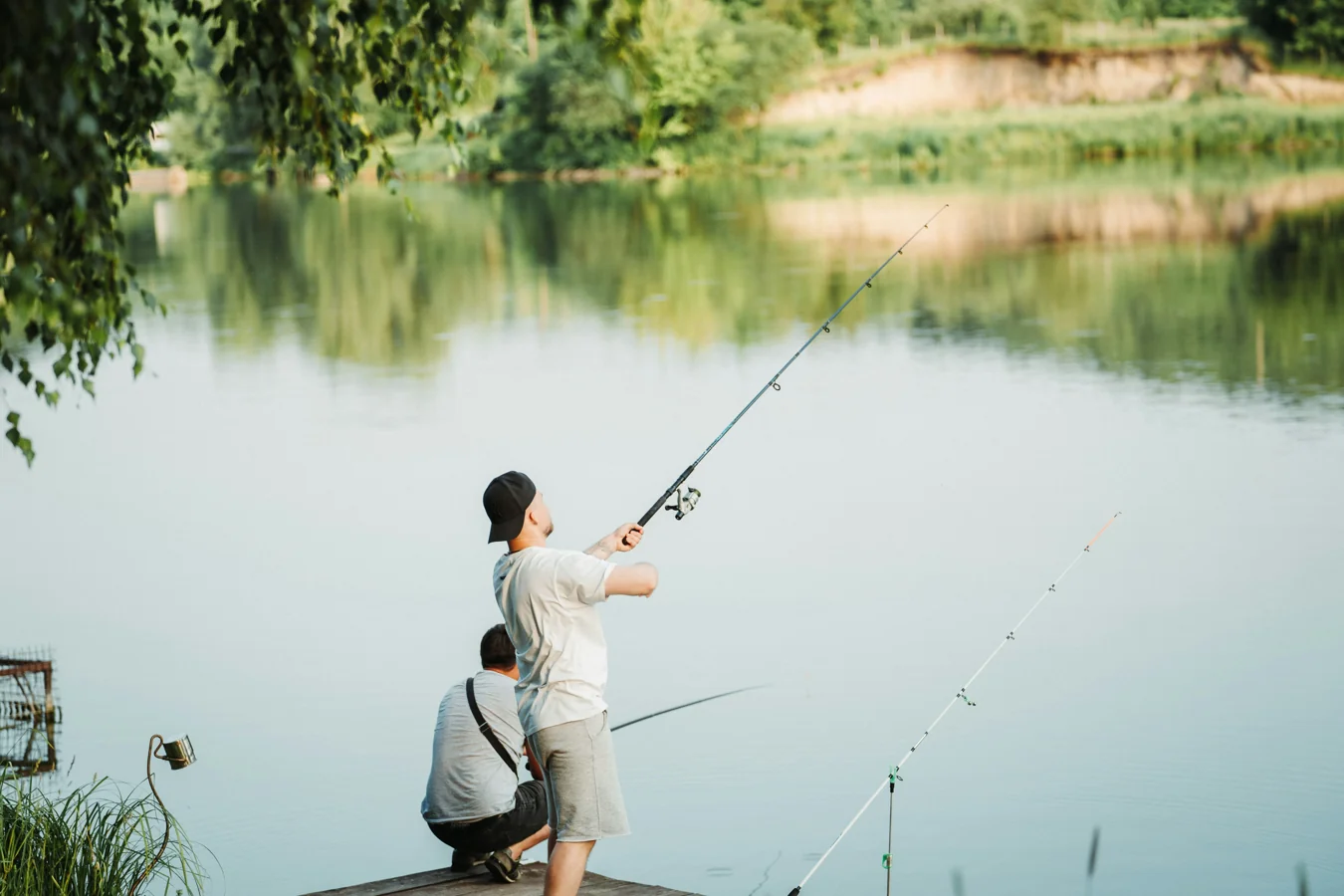 Young angler holding a bass with a smartphone filming the moment